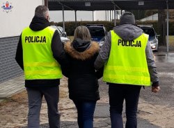 policjanci w kamizelkach prowadzą zatrzymanego mężczyznę