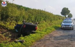 Auto leżące w rowie na drodze stoi radiowóz policyjny