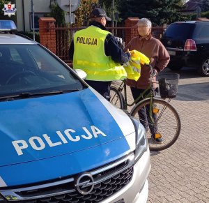 Policjant przekazuje kamizelkę rowerzystce