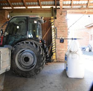 pomieszczenie gospodarcze stojący traktor z podpiętymi workami big bag