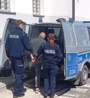 policjanci i wsiadający do policyjnego radiowozu sprawca znęcania
