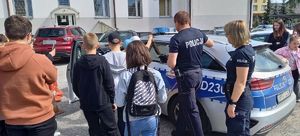 dzieci stojące przy policyjnym radiowozie