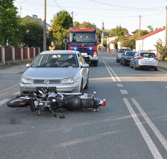samochód stojący na drodze i leżący przed nim motocykl