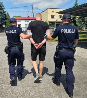 dwóch policjantów prowadzi zatrzymanego mężczyznę