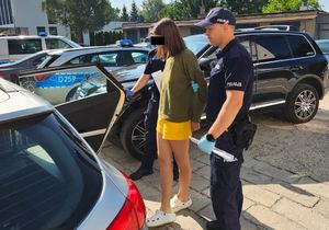 Policjanci prowadzą zatrzymana kobietę.