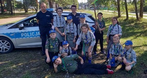 grupa harcerzy z policjantami w tle policyjny radiowóz