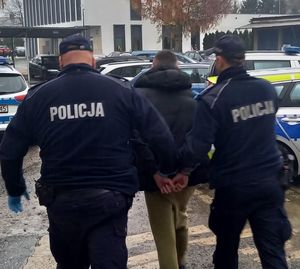 policjanci prowadzą osobę zatrzymaną