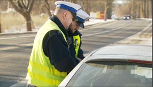 dwóch umundurowanych policjantów prowadzących kontrole drogowe