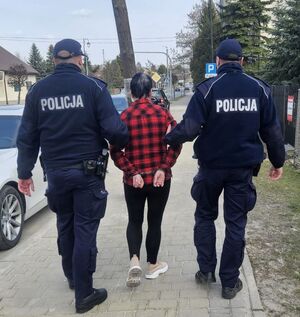 dwóch policjantów prowadzi kobietę do sądu