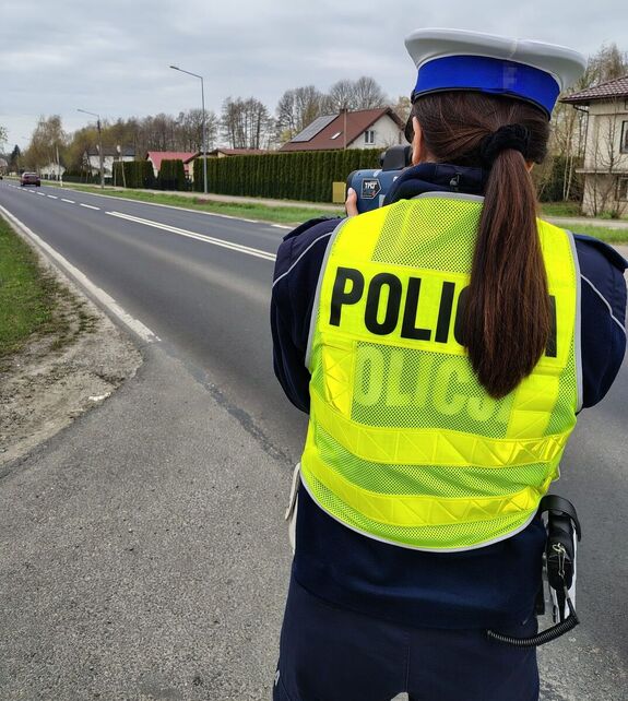 umundurowana policjantka trzyma w ręku urządzenie do pomiaru prędkości