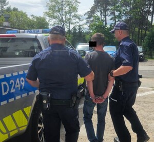 dwóch umundurowanych policjantów prowadzi zatrzymanego sprawcę znęcania