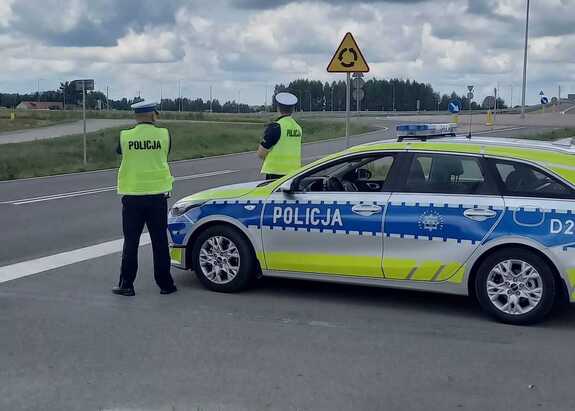 dwóch umundurowanych policjantów obok radiowozu